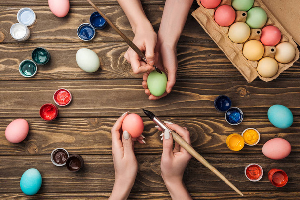 top view of women painting easter eggs at wooden table - Foto, imagen