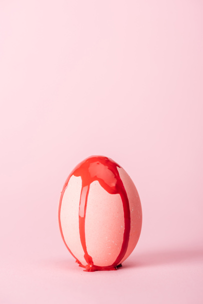 easter egg with red paint spills on pink with copy space - Foto, immagini