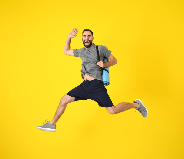 Молодий спортивний чоловік стрибає на кольоровому фоні
 - Фото, зображення
