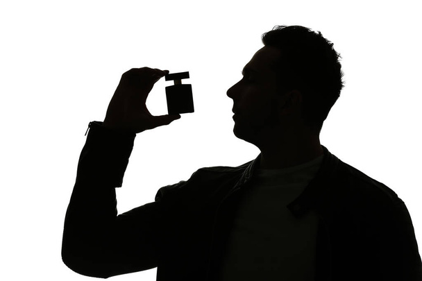 Siluetti komea mies pullo hajuvettä valkoisella pohjalla
 - Valokuva, kuva