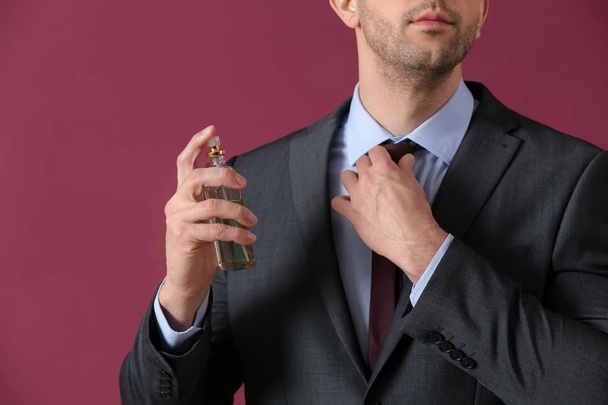 Hombre guapo con botella de perfume sobre fondo de color, primer plano
 - Foto, Imagen