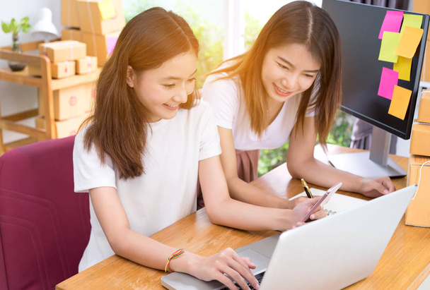 Fiatal ázsiai lány csapatmunka együtt szabadúszó üzleti saját otthon dolgozik a hivatal-val a laptop, a Megjegyzés, a mobil, csomagolás, szállítás online piaci beszerzési rendelések ügyfél ellenőrzése. - Fotó, kép