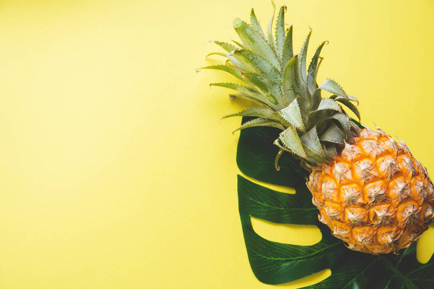 Fresh ripe pineapple and leaf of monstera tree on color background, top view - 写真・画像