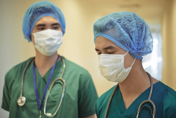 Team of medical wokers in scrubs, masks and medical hats ready for surgery - Photo, Image
