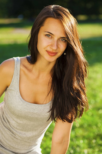 Young brunette woman in summer park - Фото, изображение