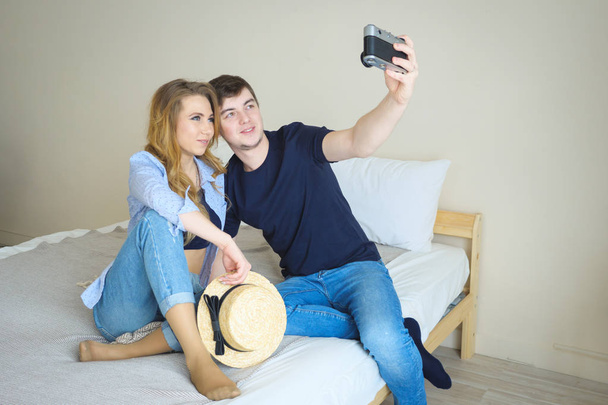 meisje jongen zitten op bed maken selfie met oude camera poseren - Foto, afbeelding