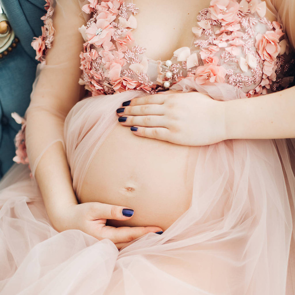 Hermosa mujer embarazada cogida de la mano en el estómago en el corazón
. - Foto, imagen