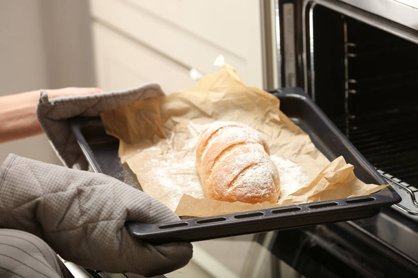 Bakplaat met zelfgebakken brood uit de oven halen - Foto, afbeelding