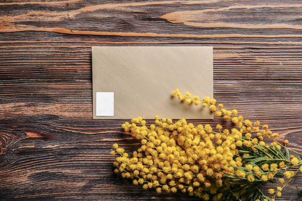 Красивые цветы мимозы с конвертом на деревянном столе
 - Фото, изображение