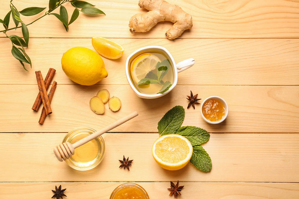 Чашка горячего чая с лимоном, имбирем и медом на деревянном столе
 - Фото, изображение