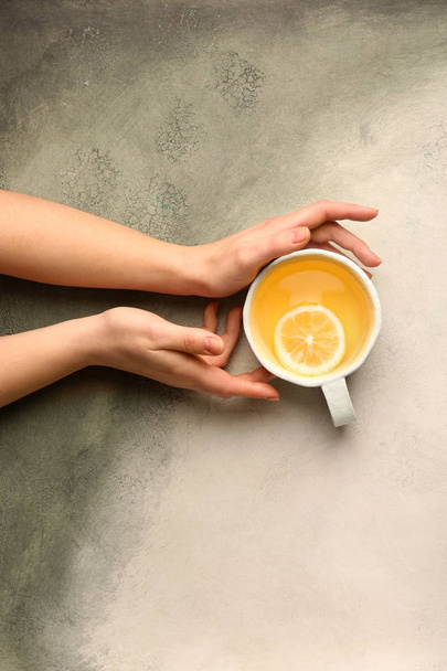 Vrouwelijke handen met kopje smakelijke thee op lichte achtergrond - Foto, afbeelding