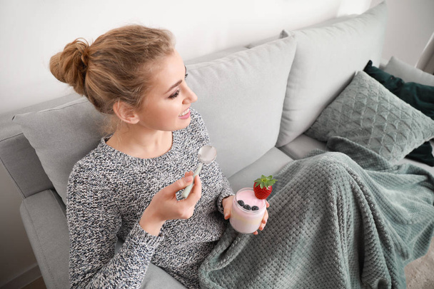 Jeune femme manger du yaourt savoureux à la maison
 - Photo, image