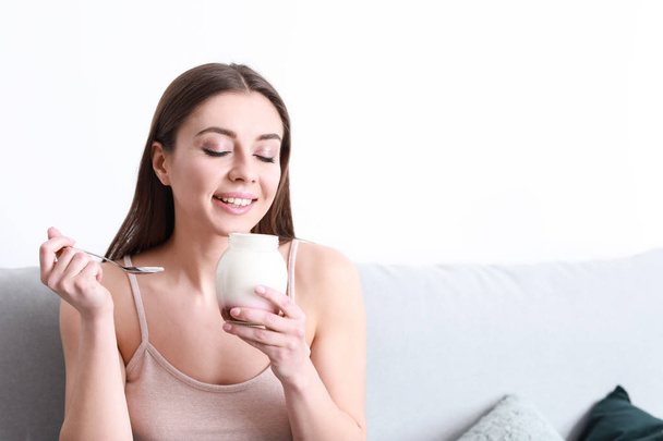 Молодая женщина ест вкусный йогурт дома
 - Фото, изображение