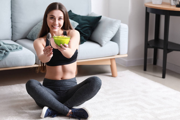 Sporty woman eating tasty yogurt at home - Photo, Image