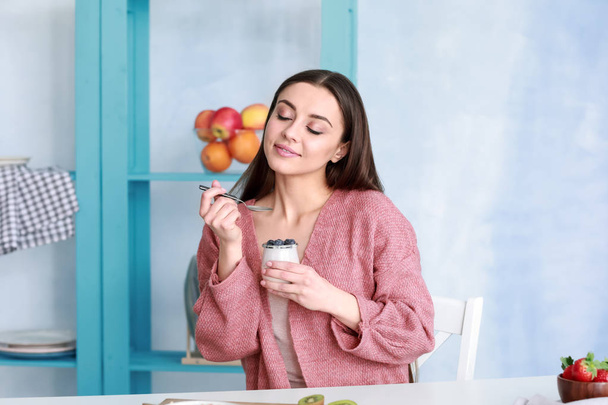 Молода жінка їсть смачний йогурт вдома
 - Фото, зображення