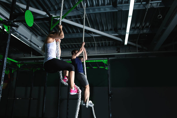 Jeune couple sportif grimpant la corde dans la salle de gym
 - Photo, image