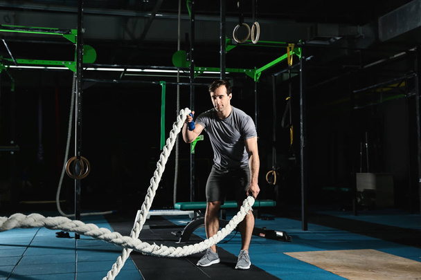 Jeune homme sportif faisant de l'exercice de corde de combat dans la salle de gym
 - Photo, image