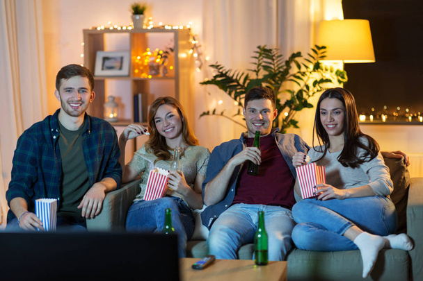 friends with beer and popcorn watching tv at home - Фото, изображение