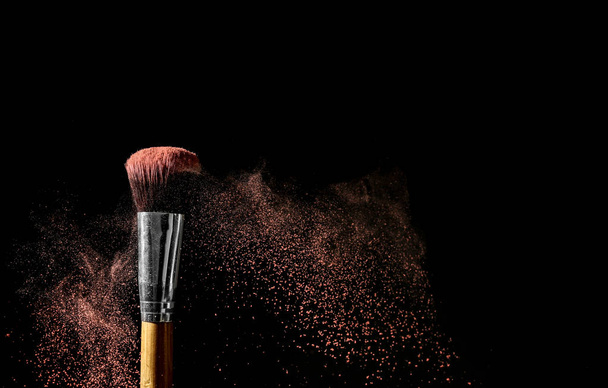 Make-up borstel en uitbarsting van eyeshadows op donkere achtergrond - Foto, afbeelding