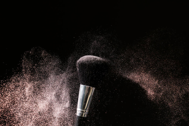 Makeup brush and burst of eyeshadows on dark background - Photo, Image