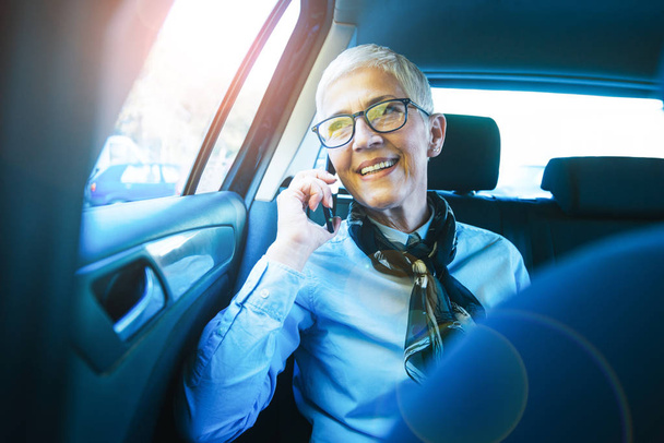 Γυναίκα που μιλάει στο τηλέφωνο ενώ ταξιδεύετε με το αυτοκίνητο. - Φωτογραφία, εικόνα