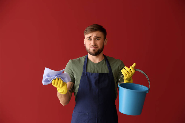 Decepción hombre perezoso con los suministros de limpieza en el fondo de color
 - Foto, Imagen