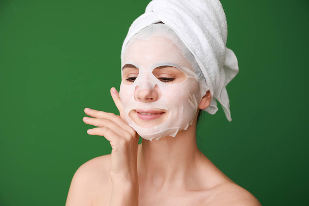 Woman with sheet facial mask on color background - Фото, зображення