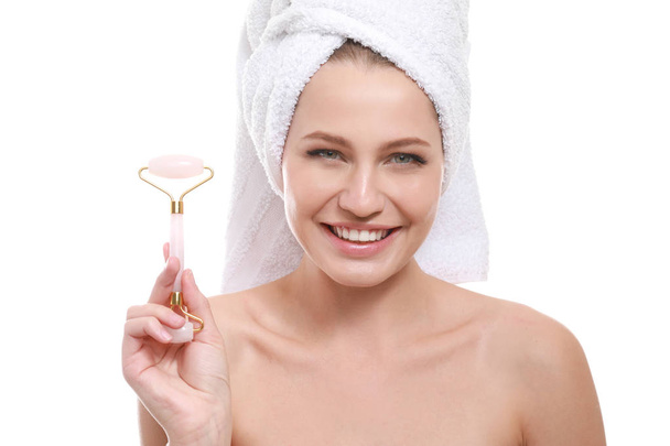 Mujer joven con herramienta de masaje facial sobre fondo blanco
 - Foto, imagen
