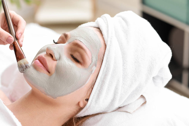 Cosmetologue appliquer un masque sur le visage de la jeune femme dans le salon de beauté
 - Photo, image