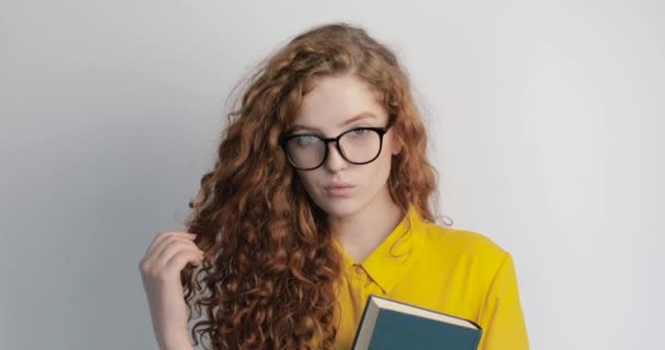 Young Student with Curly Hair Posing With Book and Glasses - Кадры, видео