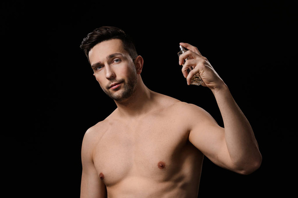 Handsome man with bottle of perfume on dark background - Fotografie, Obrázek