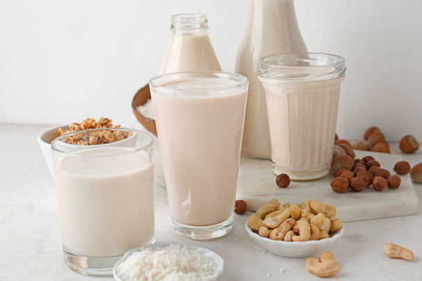 Assortiment van smakelijke veganistische melk op lichte tafel - Foto, afbeelding
