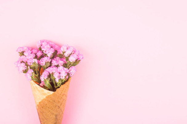 Růžové květy v oplatkovém kornoutku na zmrzlinu na růžovém pozadí. Jarní koncept. Pohled shora. byt leží, kopírovat prostor - Fotografie, Obrázek