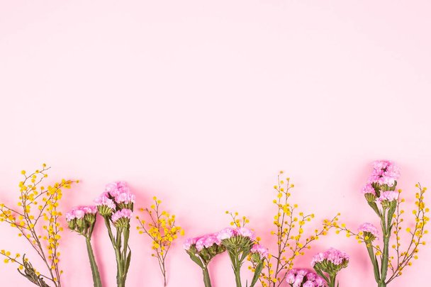 Kevät vaaleanpunainen ja keltainen kukkia vaaleanpunainen lempeä tausta. Top view, tasainen lay, kopioi tilaa
 - Valokuva, kuva