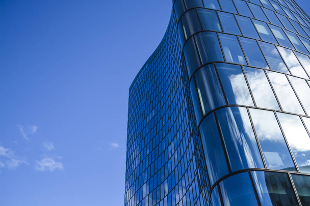 事務所ビルの近代建築。ガラスと曲線の波の形で金属から超高層ビル。青い空と住宅の窓の反射ビジネス センター. - 写真・画像