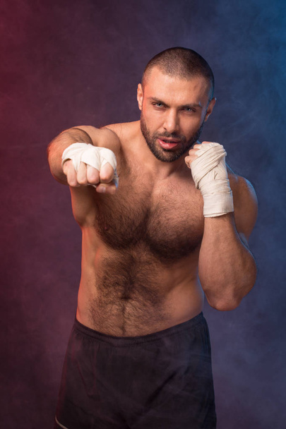 Young muscular boxing fighter training kicks. Kickboxer making a fighting exercise. - 写真・画像