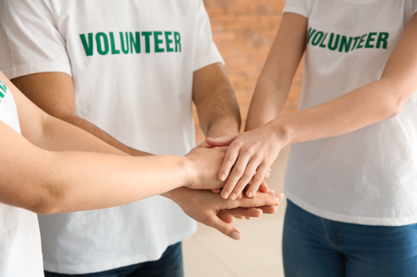 Команда молодих добровольців збирає руки в приміщенні
 - Фото, зображення