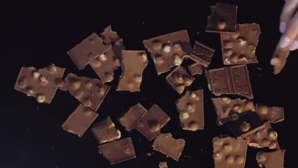 Mano de mujer pone una pieza de barra de chocolate a un montón de piezas de chocolate. Movimiento lento
 - Imágenes, Vídeo