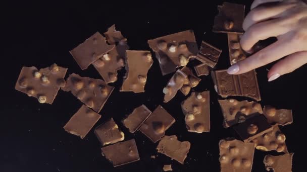 Frau Hand nimmt ein Stück Schokoriegel aus einem Bündel von Schokoladenstücken. Zeitlupe - Filmmaterial, Video