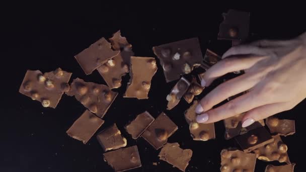 Woman hand takes one piece of chocolate bar from a bunch of chocolate pieces. Slow motion - Footage, Video