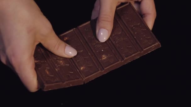 Жінка розбиває чорний шоколадний батончик з горіхами. Крупним планом. Повільний рух
 - Кадри, відео