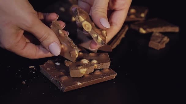 Γυναίκα σπάει μαύρη μπάρα σοκολάτας με ξηρούς καρπούς. Γκρο πλαν. Αργή κίνηση - Πλάνα, βίντεο