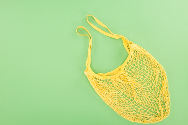top view of yellow string bag on light green background - Foto, afbeelding