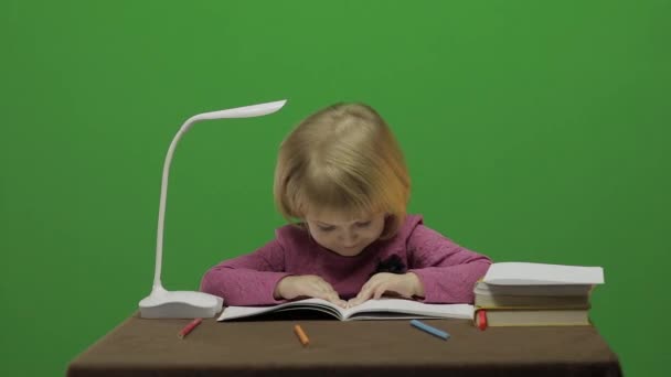 Kız masada çizim. Eğitim sürecinde sınıf. Mutlu üç yaşında bir kız. Sevimli kız gülümsüyor. Küçük çocuk, 3-4 yaşında sarışın kız. Yüzleri olun. Yeşil ekran video. Chroma Key - Video, Çekim
