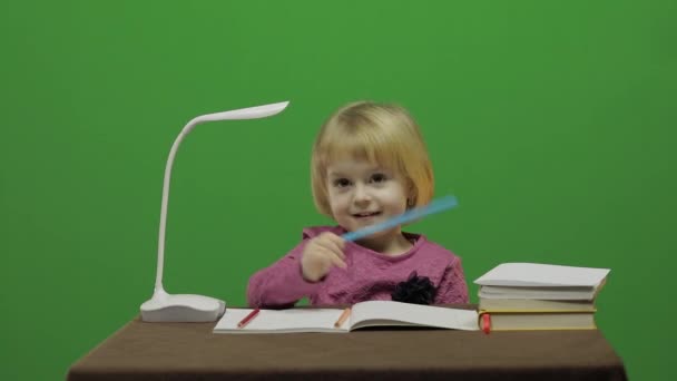 食卓を描いている女の子。教室で教育プロセス。幸せな 3 歳の女の子。笑っているかわいい女の子。3-4 歳のブロンドの女の子のかわいらしい子。顔を作る。緑色の画面のビデオ。クロマ キー - 映像、動画