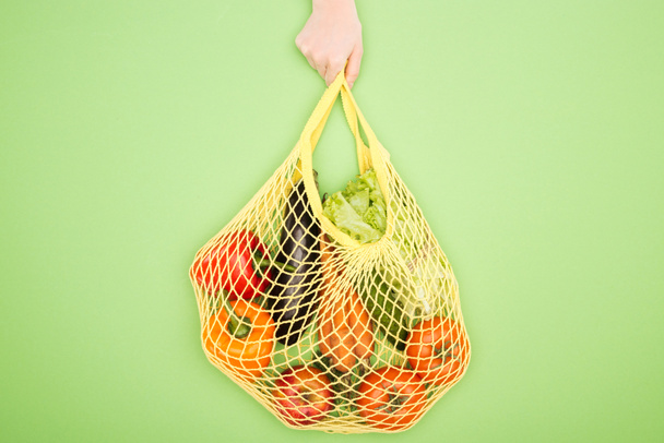 cropped view of woman holding string bag with raw vegetables - Fotografie, Obrázek