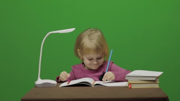 食卓を描いている女の子。教室で教育プロセス。幸せな 3 歳の女の子。笑っているかわいい女の子。3-4 歳のブロンドの女の子のかわいらしい子。顔を作る。緑色の画面のビデオ。クロマ キー - 映像、動画