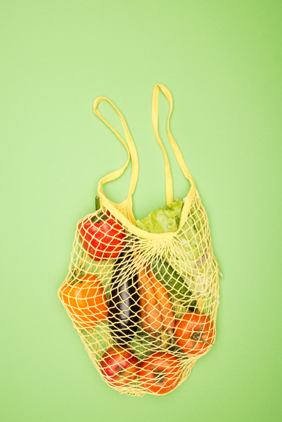 vista superior de la bolsa de hilo amarillo con verduras orgánicas maduras en la superficie verde claro
 - Foto, Imagen