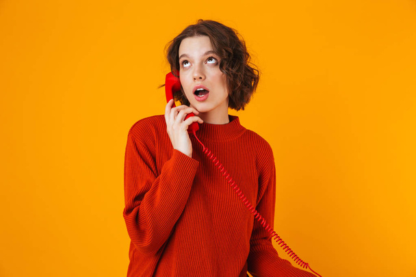 Serious young pretty woman posing isolated over yellow wall background talking by telephone. - Zdjęcie, obraz