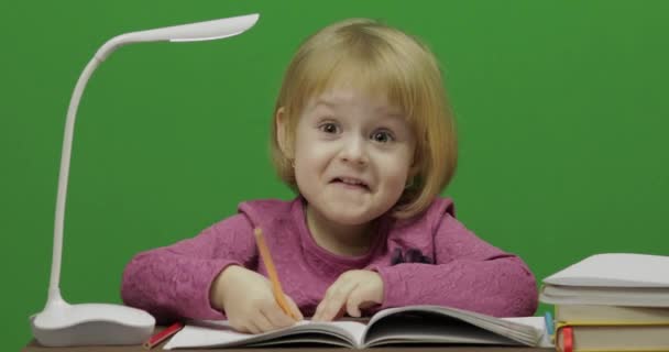 Dziewczyna Rysowanie przy stole. Proces edukacji w klasie. Szczęśliwy trzy lat dziewczyna. Ładna dziewczyna uśmiechając się. Dość małe dziecko, 3-4-letniego Blondynka. Zrobić twarze. Zielony ekran wideo. Kluczowanie kolorem - Materiał filmowy, wideo